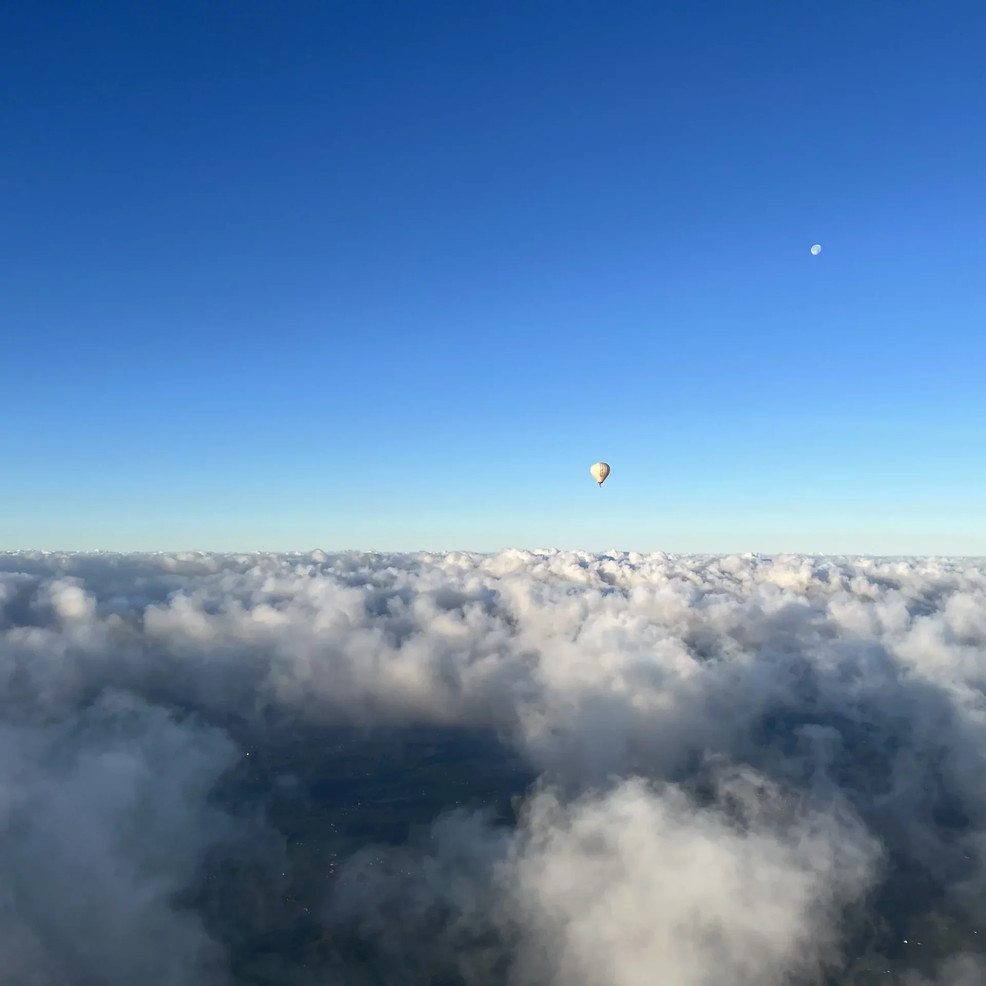 Wolken aus dem Ballonkorb mit dem Mond im Hintergrund